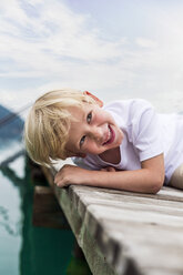 Porträt eines lächelnden kleinen Jungen, der auf einem Bootssteg liegt - DAWF000141