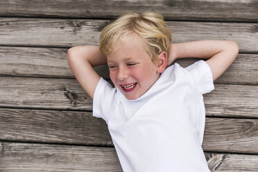 Porträt eines lachenden kleinen Jungen, der auf einem Steg liegt - DAWF000112