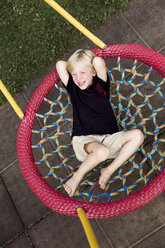 Porträt eines kleinen Jungen, der sich auf einem Spielplatzgerät ausruht - DAWF000118