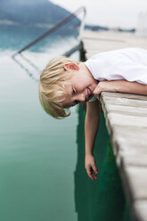 Portrait of smiling little boy lying on a jetty - DAWF000122