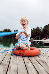 Portrait of laughing little boy playing with a lifesaver on a jetty - DAWF000128