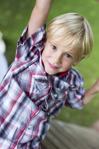 Porträt eines lächelnden kleinen Jungen, der auf ein Spielplatzgerät klettert, lizenzfreies Stockfoto