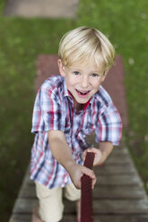 Porträt eines lächelnden kleinen Jungen, der auf einem Spielplatz klettert - DAWF000135