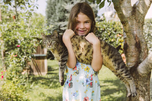 Mädchen hält Katze im Garten - MFF001267