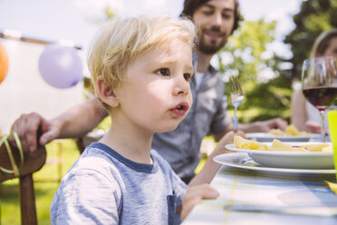 Junge isst Nudeln mit Familie am Gartentisch - MFF001245