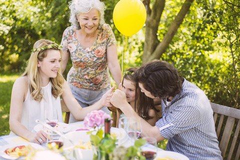 Family of three generations congratulating girl on a garden party stock photo