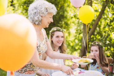 Großmutter serviert Tochter und Enkelin Nudeln auf einer Gartenparty - MFF001258