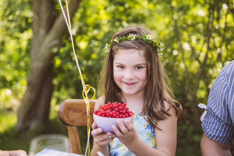 Mädchen hält Schale mit roten Johannisbeeren im Garten, lizenzfreies Stockfoto