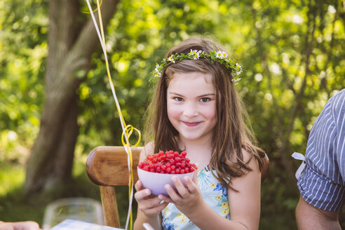 Mädchen hält Schale mit roten Johannisbeeren im Garten - MFF001264