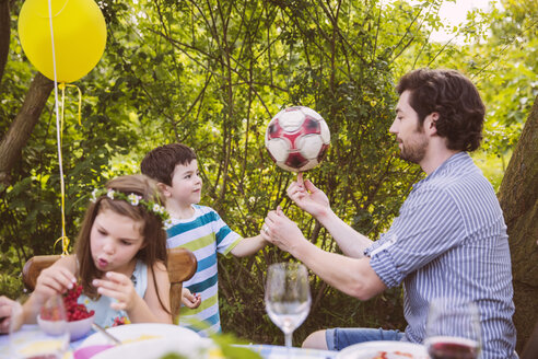 Vater und Sohn spielen mit Fußball auf einer Gartenparty - MFF001268