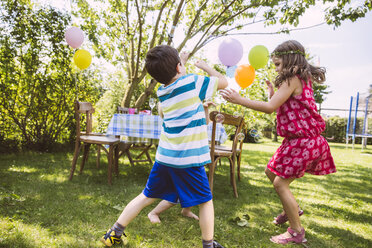 Children trying to catch soap bubbles in garden - MFF001274