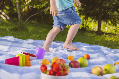 Boy walking on a picnic blanket with fruit stock photo