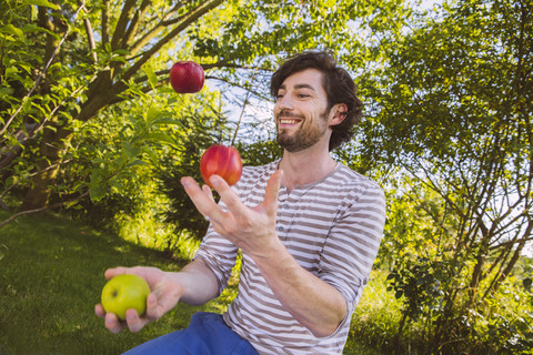 Man juggling with fruit in garden stock photo