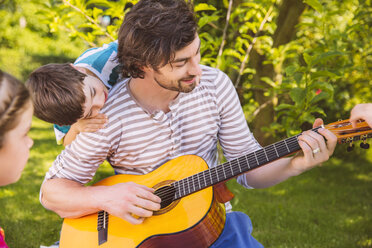 Father with children playing guitar in garden - MFF001325