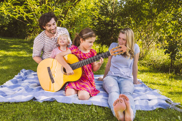 Familie auf Picknickdecke spielt Gitarre - MFF001305