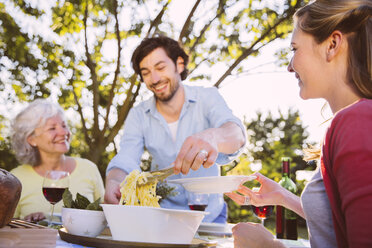 Ehepaar und ältere Frau beim Abendessen im Garten - MFF001310