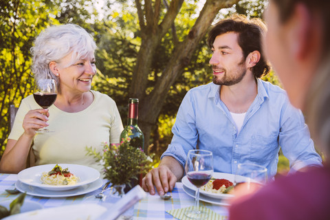 Ehepaar und ältere Frau beim Abendessen im Garten, lizenzfreies Stockfoto