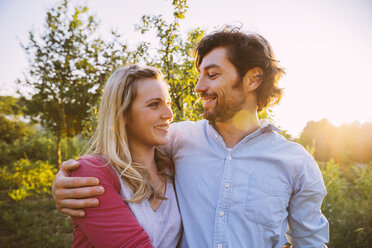 Couple hugging in garden in evening light - MFF001324