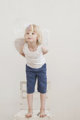 Portrait of little boy with angle wings watching a soap bubble - MJF001345