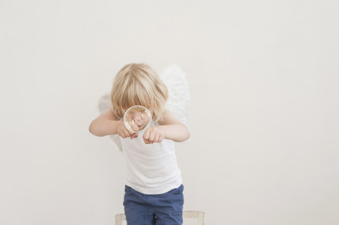 Porträt eines kleinen Jungen mit Winkelflügeln im Kampf gegen eine Seifenblase, lizenzfreies Stockfoto