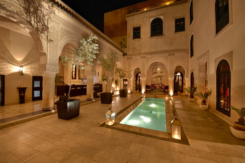 Marokko, Fes, Hotel Riad Fes, Innenhof mit beleuchtetem Pool bei Nacht - KMF001430
