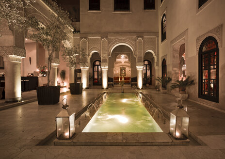 Marokko, Fes, Hotel Riad Fes, Innenhof mit beleuchtetem Pool bei Nacht - KMF001464