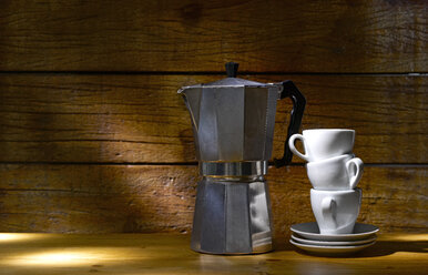 Espresso can and stack of three espresso cups in front of wooden wall - KSWF001330