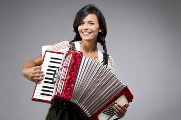 Portrait of smiling young woman playing accordion - MAEF009043