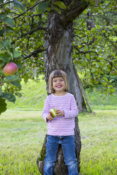Porträt eines kleinen Mädchens, das sich an einen Apfelbaum lehnt - LVF001797