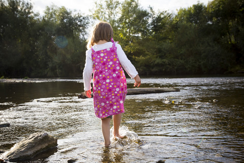 Kleines Mädchen spielt am Flussufer, lizenzfreies Stockfoto