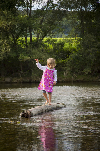 Little girl balancing on a rock in a river stock photo