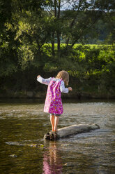 Little girl balancing on a rock in a river - LVF001803