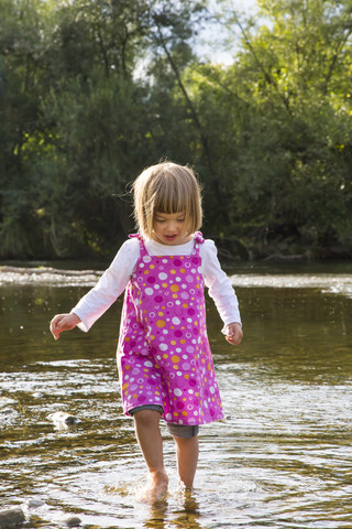 Kleines Mädchen geht im Wasser am Flussufer, lizenzfreies Stockfoto