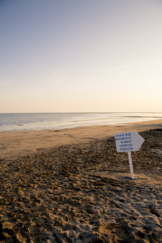 Italy, Gorizia, Grado, view to sandy beach with direction sign at evening twilight stock photo