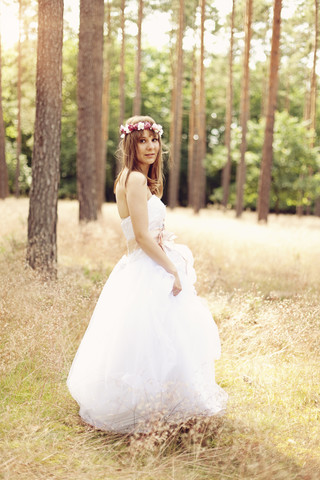Braut in weißem Hochzeitskleid und Blumen auf einer Wiese, lizenzfreies Stockfoto