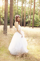 Bride wearing white wedding dress and flowers walking on a meadow - AFF000076