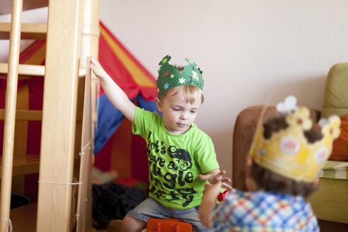 Zwei kleine Jungen mit Papierkronen spielen im Kinderzimmer - AFF000077