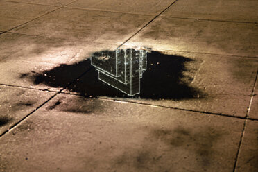 USA, Kalifornien, San Francisco, Spiegelung eines Wolkenkratzers in einer Pfütze bei Nacht - BRF000779