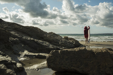 Frankreich, Bretagne, Camaret-sur-Mer, Jugendlicher mit Surfbrett am Meer - UUF001651