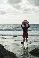 Frankreich, Bretagne, Camaret-sur-Mer, Jugendlicher mit Surfbrett am Meer - UUF001652