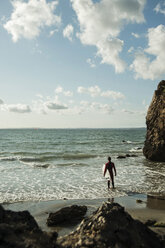 Frankreich, Bretagne, Camaret-sur-Mer, Jugendlicher mit Surfbrett am Meer - UUF001663