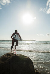 Frankreich, Bretagne, Camaret-sur-Mer, Jugendlicher mit Surfbrett am Meer - UUF001666