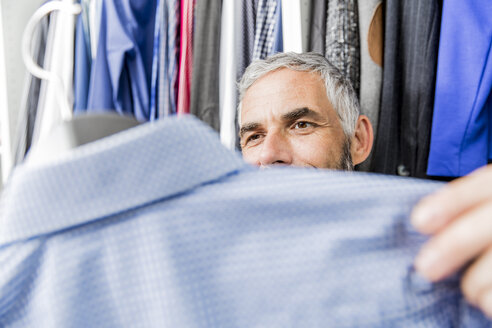 Man choosing jacket at his walk-in closet - MBEF001212