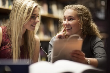 Two female students with digital tablet in a library - ZEF000830