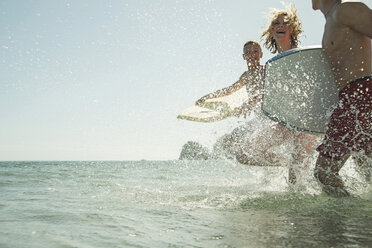 Drei Teenager mit Surfbrettern laufen am Ufer des Meeres - UUF001687