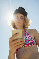 Teenage girl using her smartphone on the beach - UUF001692