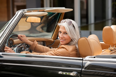 Porträt einer reifen Frau, die in einem Cabrio sitzt, lizenzfreies Stockfoto