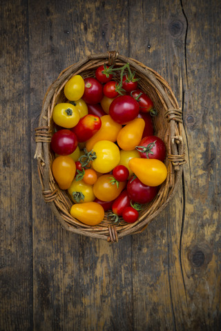 Korb mit verschiedenen Bio-Heirloom-Tomaten auf Holztisch, lizenzfreies Stockfoto