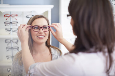 Frau beim Optiker, die eine Brille anprobiert - ZEF000638