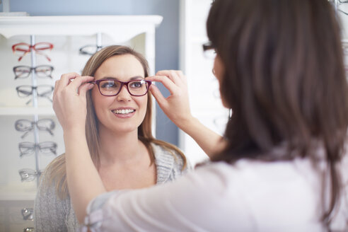 Frau beim Optiker, die eine Brille anprobiert - ZEF000638